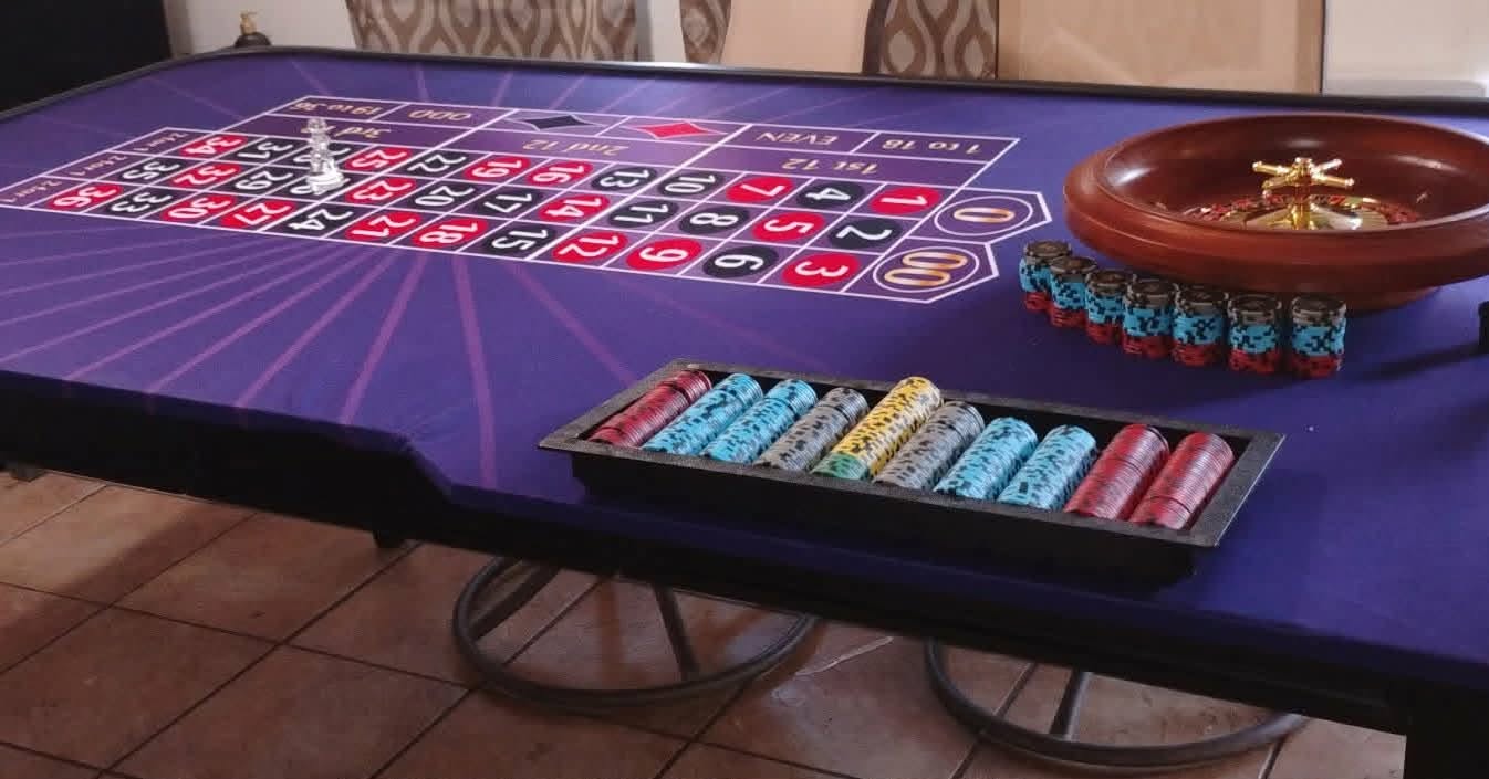 Purple roulette table prepared with chips and roulette wheel
